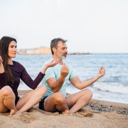 Un homme et une femme en méditation au bord de la plage