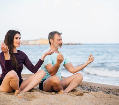 Un homme et une femme en méditation au bord de la plage