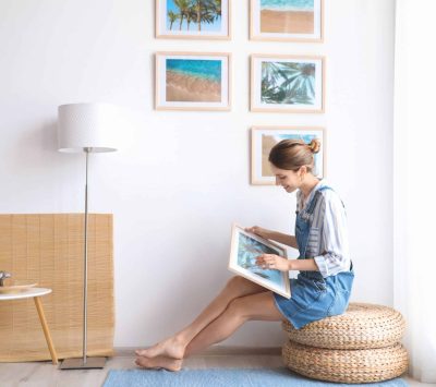 Femme qui met des tableaux sur le mur