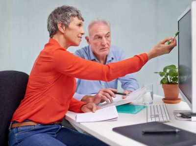 Un homme et une femme regardant un ordinateur avec des papier en main