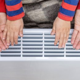 Une femme et un enfant ce réchauffent les mains sur un radiateur