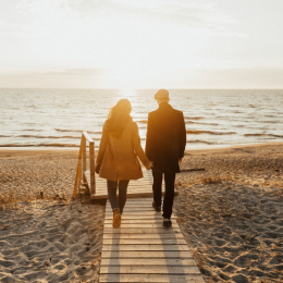 Un couple se tient la main et marche vers la mer