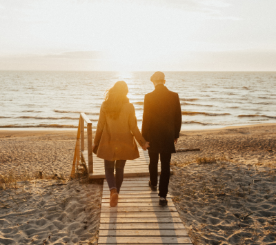 Un couple se tient la main et marche vers la mer